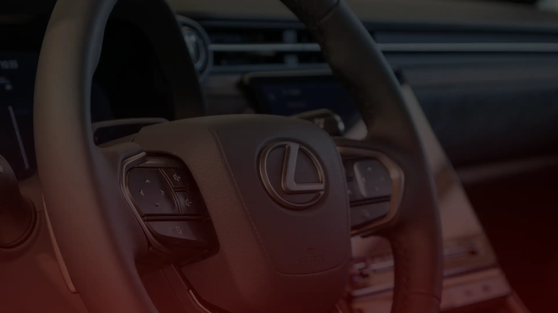 Close-up of a car dashboard highlighting a steering wheel adorned with the Lexus logo. The wheel hosts multiple controls, while the sleek interior reveals air vents and a digital display. A Toronto Acura mechanic might also appreciate its dark color scheme accented by subtle red lighting. EuroMechanic | McDermott Motors Auto | Top Reviewed Auto Repair Shop in Toronto | Visit mcdermottmotors.com