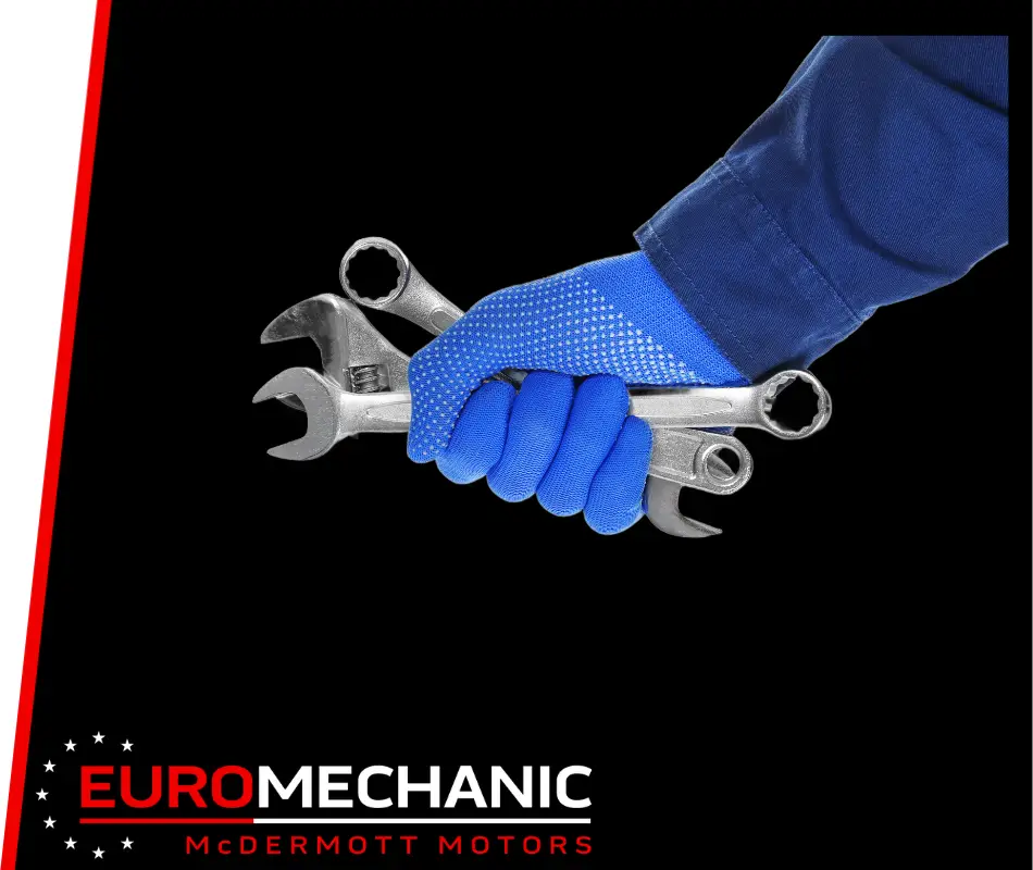 A person wearing a blue glove holds various wrenches against a black background, symbolizing expert car repair in Toronto. The text EUROMECHANIC and MCDERMOTT MOTORS appears at the bottom with a red and white design, showcasing preventative maintenance expertise. EuroMechanic | McDermott Motors Auto | Top Reviewed Auto Repair Shop in Toronto | Visit mcdermottmotors.com