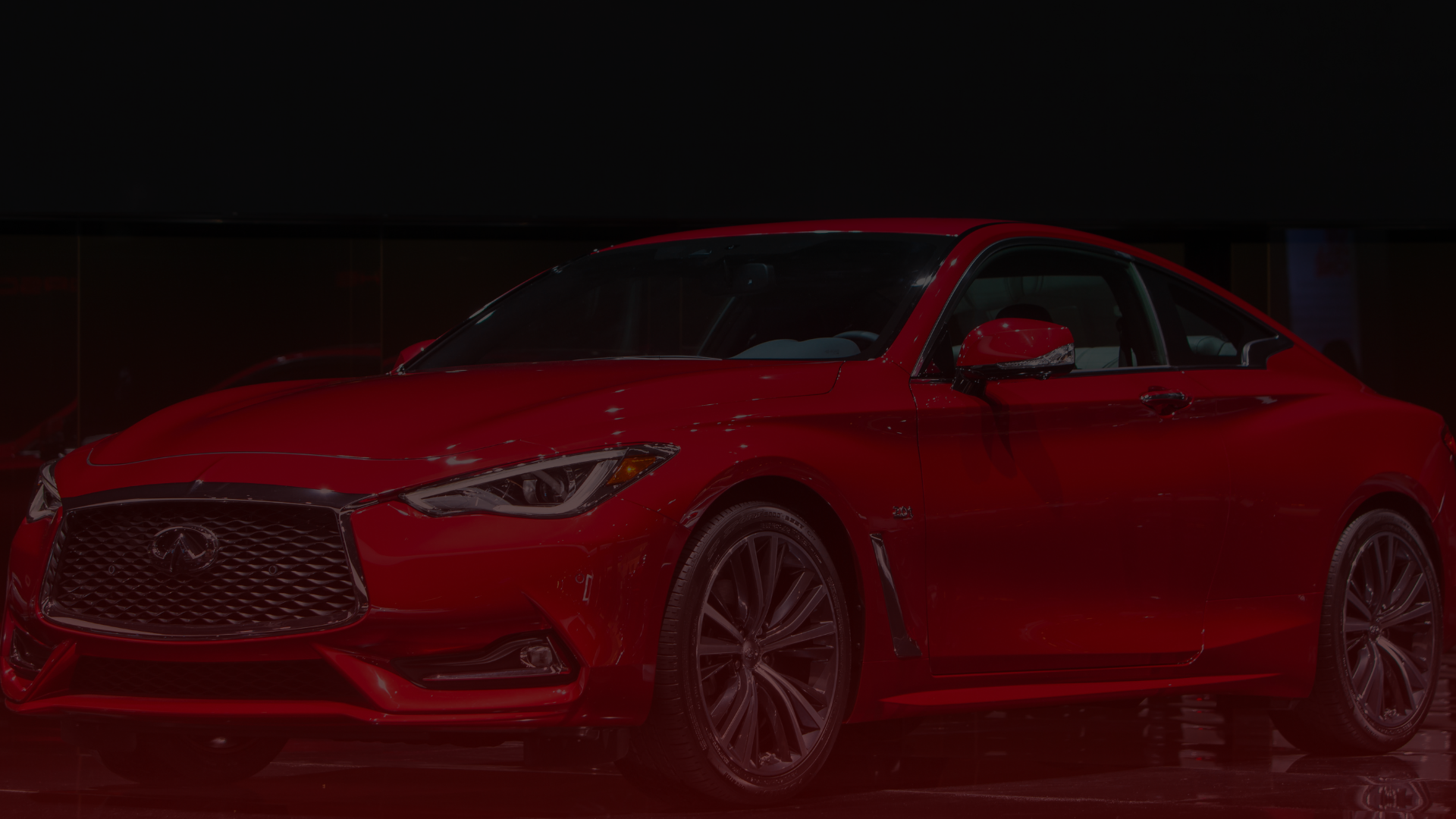 A sleek, red sports car with a shiny exterior is parked indoors under soft lighting at a Toyota mechanics garage in Toronto. The car features a prominent front grille, stylish alloy wheels, and curved lines that enhance its sporty appearance. EuroMechanic | McDermott Motors Auto | Top Reviewed Auto Repair Shop in Toronto | Visit mcdermottmotors.com