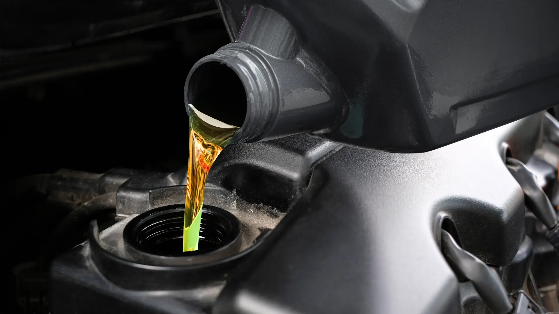 Close-up of motor oil being poured from a black container into a car engine. The oil is a golden color, flowing into the engines open cap. The engine is metallic with a sleek black finish. EuroMechanic | McDermott Motors Auto | Top Reviewed Auto Repair Shop in Toronto | Visit mcdermottmotors.com